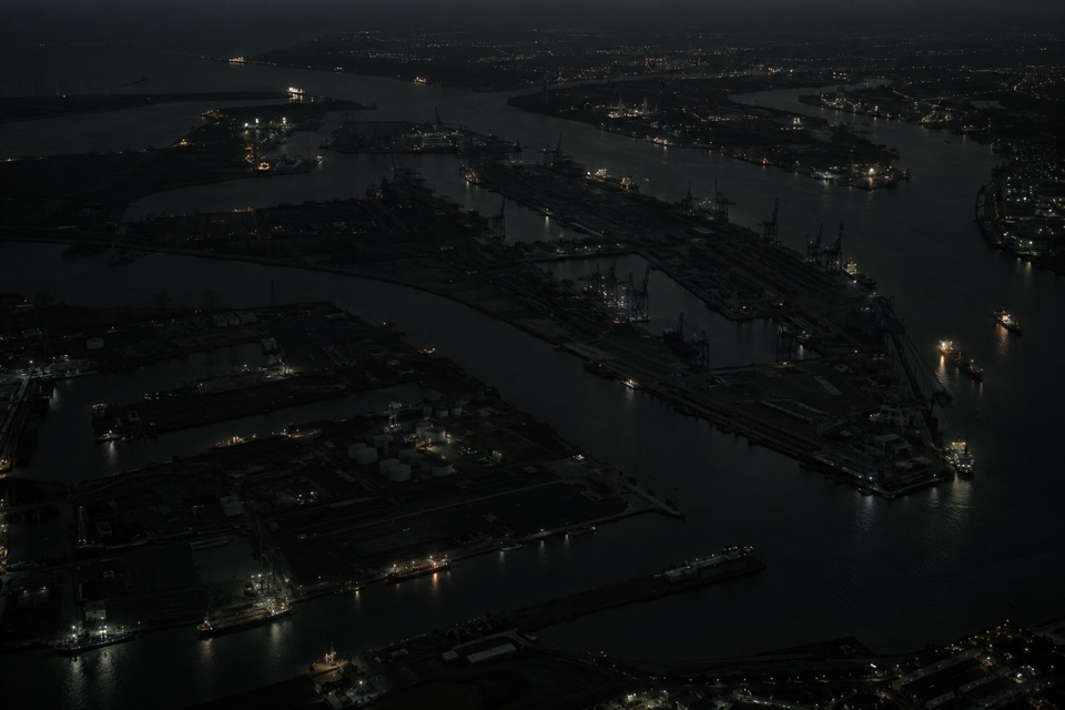 Aerial reconstruction of Rotterdam port at night, with most infrastructure dark and isolated lights.